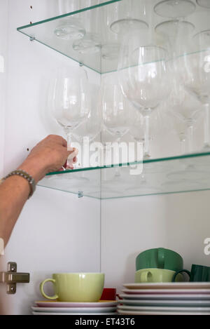 Close-up of a woman taking wineglass from cupboard, Munich, Bavaria, Germany Stock Photo