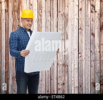 smiling male builder in helmet reading blueprint Stock Photo