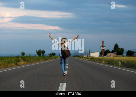 Young woman with open arms on the street at sunset Stock Photo