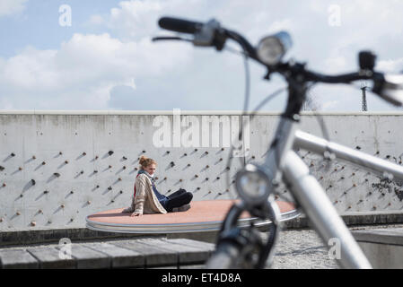 Young woman in theme park with bike in foreground Munich Bavaria Germany Stock Photo