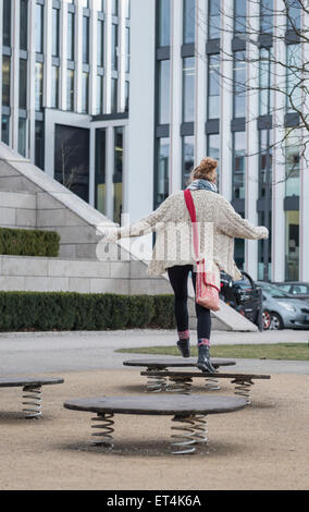 Young woman jumping on trampoline in playground Munich Bavaria Germany Stock Photo