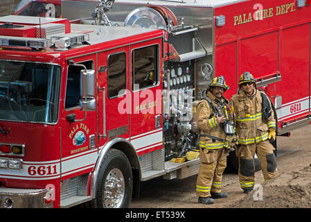 Pala Fire Department Fire Engine and Two Firefighters Wearing Turnouts Standing Next to Engine Stock Photo