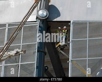 Workmen on an access platform installing mesh panels, South Stand expansion works, Etihad Stadium, Manchester, England, UK Stock Photo