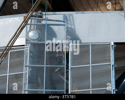 Workmen on an access platform installing mesh panels, South Stand expansion works, Etihad Stadium, Manchester, England, UK Stock Photo