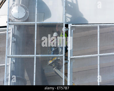 Workmen on an access platform installing mesh panels, South Stand expansion works, Etihad Stadium, Manchester, England, UK Stock Photo