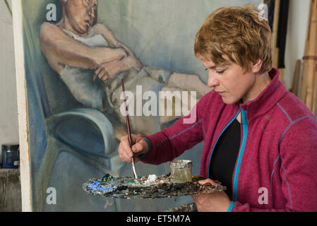 Woman mixing colors while painting, Bavaria, Germany Stock Photo