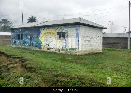 painted cinder block building with fading mural extending along side wall identifying it as a Zapatista autonomous school Chiapa Stock Photo