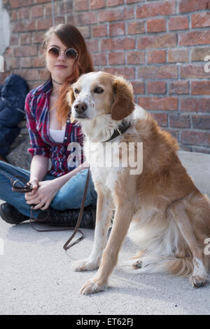 Young woman with dog in front of brick wall, Munich, Bavaria, Germany Stock Photo