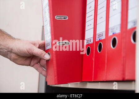 Man taking confidential file from filing cabinet, Munich, Bavaria, Germany Stock Photo