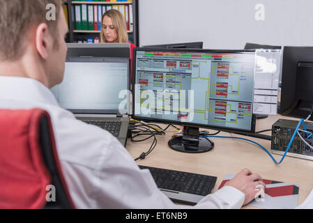 Man working in office with his colleague in background, Munich, Bavaria, Germany Stock Photo
