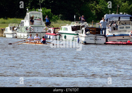 A coxed pair rowing crew row past pleasure boats which are moored on the banks of The River Thames at Windsor. Stock Photo