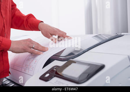 Woman using photocopier in office, Munich, Bavaria, Germany Stock Photo