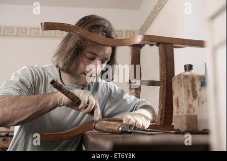 Carpenter repairing an antique wooden chair at workshop, Bavaria, Germany Stock Photo