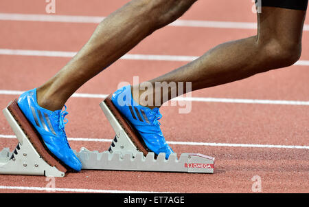 A male athlete (African ethnicity) is getting ready at the starting block on an athletics race track just before the the start Stock Photo