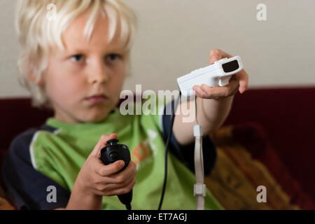 7 year old boy at home playing Nintendo Wii computer game with Nintendo game controller in his hand. Stock Photo