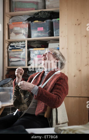 Senior female fashion designer stitching cap in workshop Bavaria Germany Stock Photo