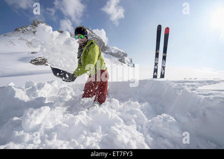 Man shovelling snow for bivouac camp, Tyrol, Austria Stock Photo