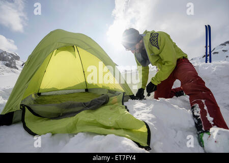 Man constructing tent in snow, Tyrol, Austria Stock Photo