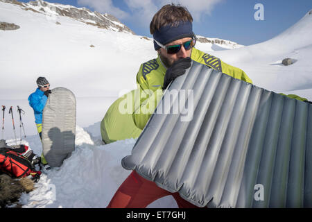 Two men blowing into air mattresses for camping, Tyrol, Austria Stock Photo