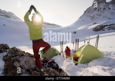 Rear view of man doing yoga at sunrise while camping on mountain, Tyrol, Austria Stock Photo