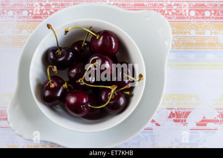 Fresh Coral cherries, Prunus, in a white bowl on a patterned background Stock Photo