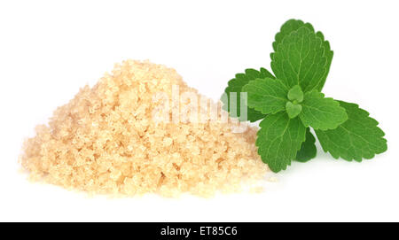 Coarse crystals of brown sugar with stevia leaves over white background Stock Photo