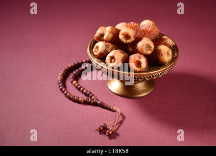 Dates in a bowl and islamic prayer beads. Stock Photo