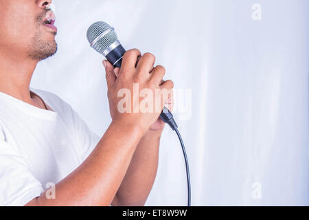 Young man holding a microphone and singing. Stock Photo
