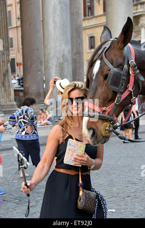 A pretty woman takes a selfie with a horse outside the Pantheon in Rome, Italy Stock Photo