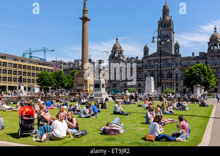 Glasgow, Scotland, UK. 12th June, 2015. At lunch time many people from the city centre offices, shoppers and tourists are enjoying their break by sunbathing in the open areas of George Square, in Glasgow city centre where with sunny skies, the temperature soared to 24C Credit:  Findlay/Alamy Live News Stock Photo
