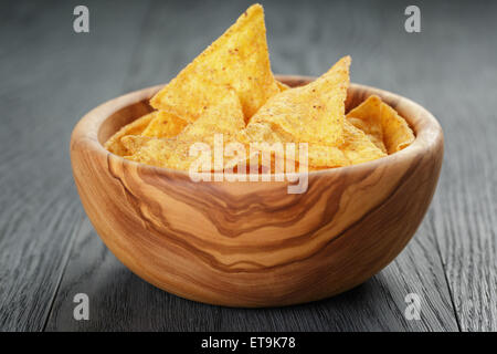 tortilla chips in olive wood bowl on wooden table Stock Photo