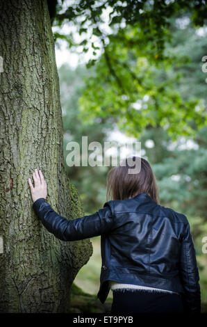 Young woman leaning against a tree Stock Photo