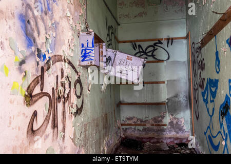 Small room with graffiti on the walls with an electrical control box vandalised on the wall Stock Photo
