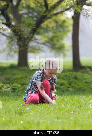 Little girl picking daisies in one of the parks in London Stock Photo