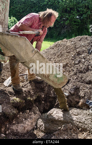 UK. A builder pouring concrete for the foundations of a garden summerhouse Stock Photo