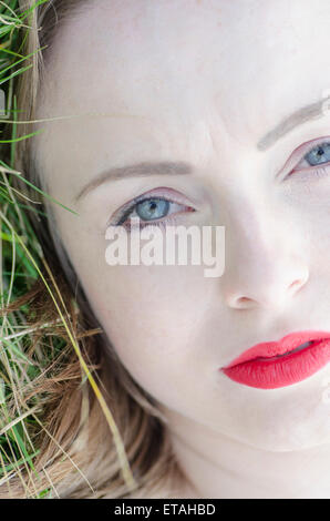 Serious young woman lying down on the grass Stock Photo
