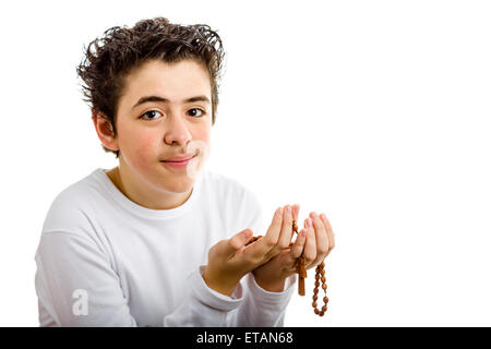 A Caucasian boy is praying and he holds Rosary beads with both hands Stock Photo
