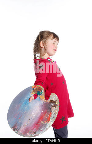 very young girl in red with palette for painting in studio against white background Stock Photo