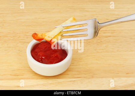 French fries on a fork dipping in tomato ketchup Stock Photo