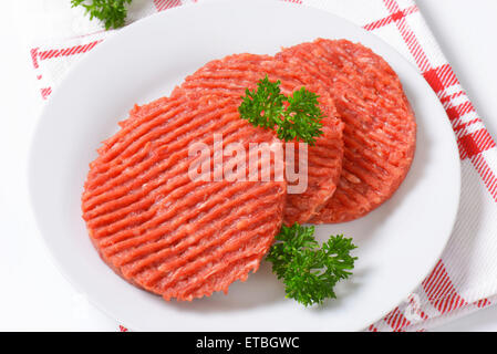 fresh hamburger patties on white plate Stock Photo