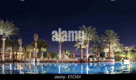 resort and luxury getaway hotel view of water swimming pool at night, with Arabian style palm desert oasis, shot in dubai, uae Stock Photo