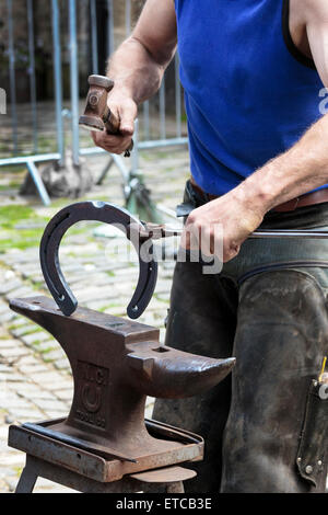 Farrier making a horseshoe and moulding it over an anvil while it was still red hot. Pollok Park, Glasgow, Scotland, UK Stock Photo