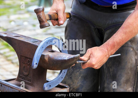 Farrier making a horseshoe and moulding it over an anvil while it was still red hot. Pollok Park, Glasgow, Scotland, UK Stock Photo