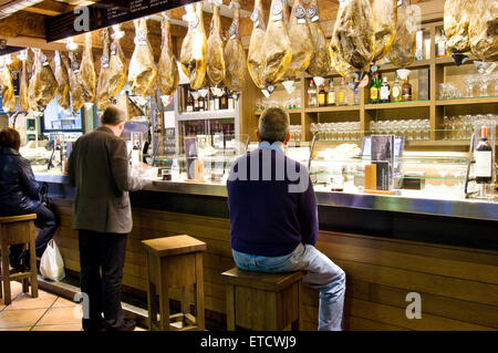 Patrons in a bar in Pamplona, Spain with jamon ham hanging from the ceiling Stock Photo