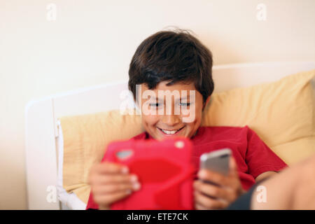 Young boy making selfie pictures with tablet and phone - with shallow depth of field Stock Photo