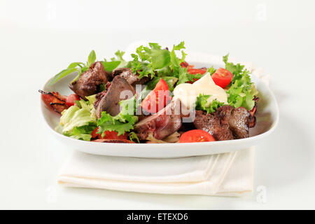 Pan fried chicken livers with salad greens and bacon strips Stock Photo