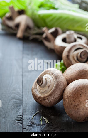 Fresh raw portobello mushrooms with rosemary and lettuce salad on wooden background Stock Photo