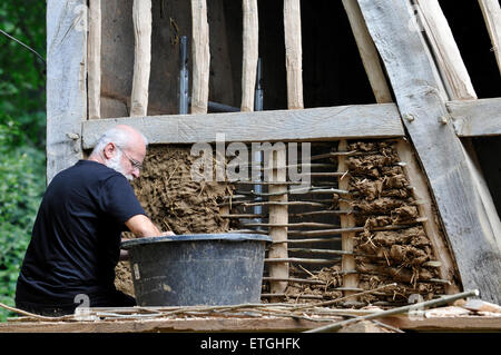 Man working with loam and straw to build a vintage half-timber house Stock Photo