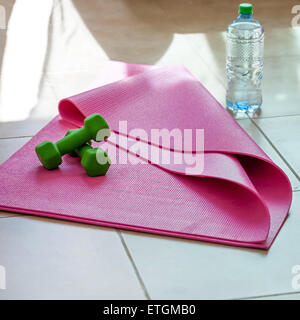 Two dumbbells with mineral water on yoga mat, healthy lifestyle concept Stock Photo