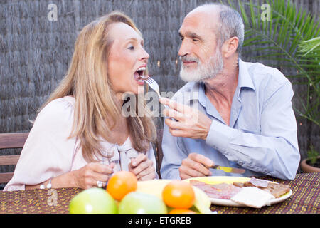 Elderly couple eating snacks in garden Stock Photo